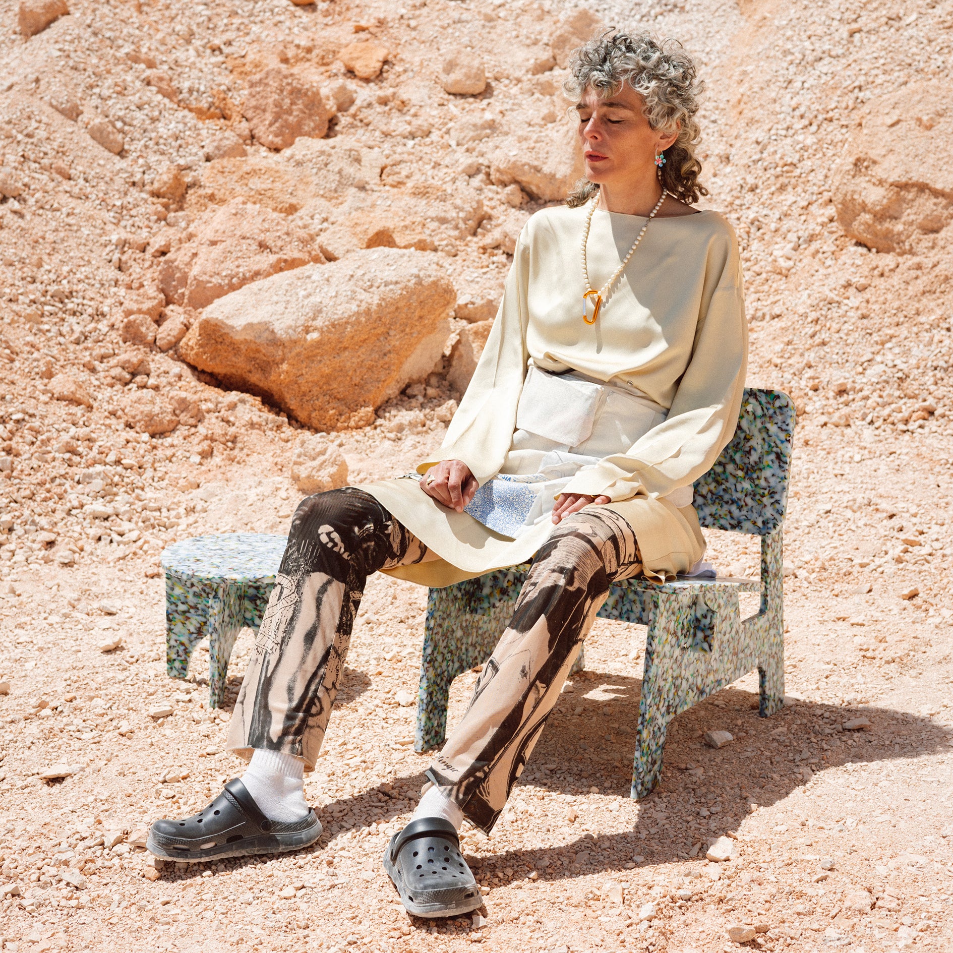 PERSON SITTING ON COLOURFUL CHAIR BY THE MINIMONO PROJECT - BRAND FOR ECO FRIENDLY - PLAYFUL - MULTI FUNCTIONAL - SUSTAINABLE - HIGH QUALITY - DESIGN FURNITURE FROM RECYCLED PLASTIC FOR BOTH ADULT AND CHILDREN MADE IN BERLIN GERMANY