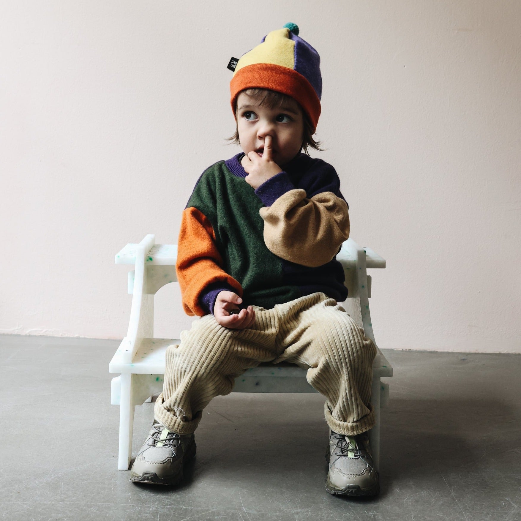 KID PICKING NOSE SITTING ON WHITE SMALL STEP STOOL BY THE MINIMONO PROJECT - BRAND FOR ECO FRIENDLY - PLAYFUL - MULTI FUNCTIONAL - SUSTAINABLE - HIGH QUALITY - DESIGN FURNITURE FROM RECYCLED PLASTIC FOR BOTH ADULT AND CHILDREN MADE IN BERLIN GERMANY